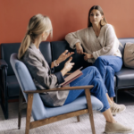 Woman sitting in a cozy therapy office in Burlington Ontario, looking thoughtful and calm