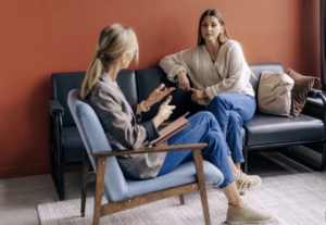 Woman sitting in a cozy therapy office in Burlington Ontario, looking thoughtful and calm
