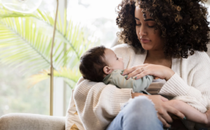 New mother sitting quietly in a sunlit room, looking tired but reflective — postpartum anxiety therapy Burlington